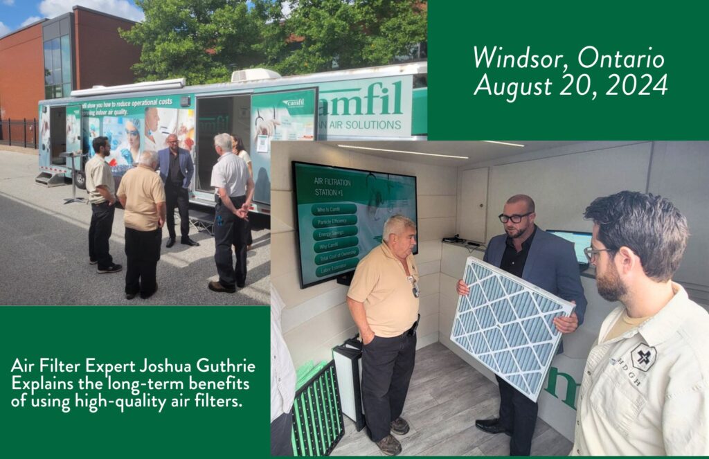 Air Filter Expert Joshua Guthrie 
Explains the long-term benefits 
of using high-quality air filters. He is holding a pleated air filter and speaking to two men who are facilities management team members. He is wearing black-rimmed glasses and a gray suit jacket with a black shirt under and black pants. The men are wearing beige polo shirts. 